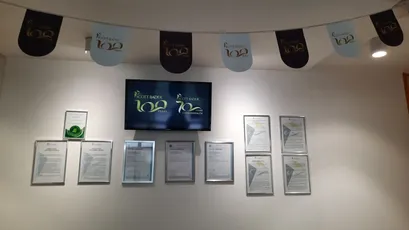 "Scott Bader corporate display with decorative bunting, digital screen showing company logo, and framed certification documents." [G]