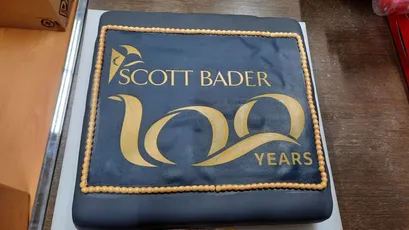 "Scott Bader 100 years celebration cake with blue fondant and gold logo, commemorating the composites and resins company" [G]