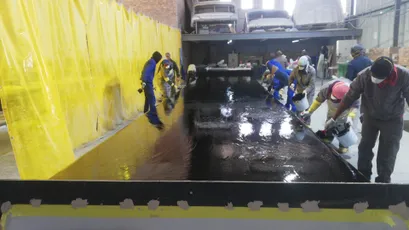 Workers applying Scott Bader resins and gelcoats during large boat hull composite manufacturing in a marine workshop. [G]