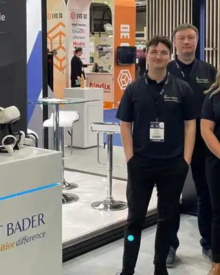 "Scott Bader team at trade exhibition showcasing composites and adhesives solutions with product displays in background" [G]
