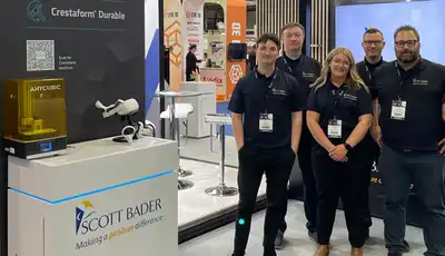"Scott Bader team at trade exhibition showcasing composites and adhesives solutions with product displays in background" [G]