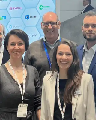 "Group of professionals at industry event with Scott Bader branding visible on hexagonal backdrop display" [G]