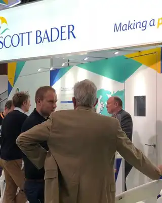 "Scott Bader exhibition stand showcasing adhesives and composites solutions, with industry professionals networking at a trade show" [G]