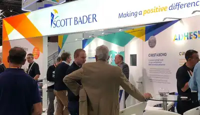 "Scott Bader exhibition stand showcasing adhesives and composites solutions, with industry professionals networking at a trade show" [G]
