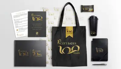 "Scott Bader 100 years commemorative merchandise collection featuring branded tote bag, notebook, travel mug and promotional materials" [G]