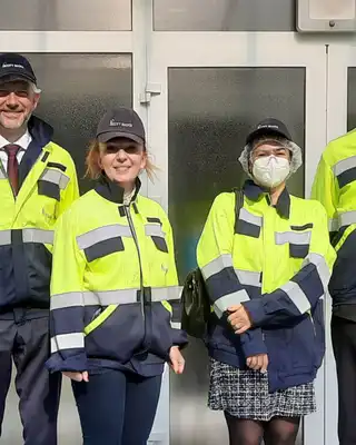 "Scott Bader office entrance with team members in high-visibility safety workwear, showcasing the company's composites facility" [G]