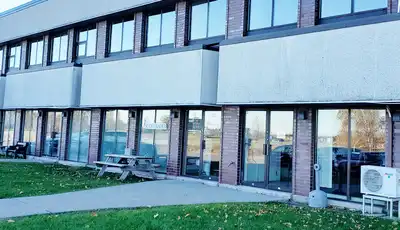 "Modern commercial building with large windows, likely a Scott Bader facility for composites and adhesives manufacturing" [G]