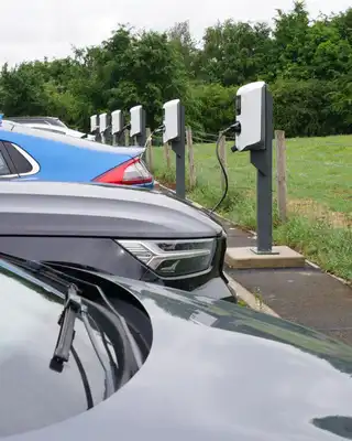 "Electric vehicle charging station with multiple cars parked in a green countryside setting" [G]