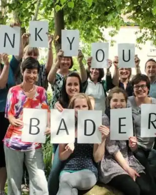 "Group holding 'THANK YOU SCOTT BADER' letter cards in outdoor setting, celebrating the company's composites and adhesives" [G]