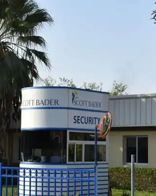 "Scott Bader manufacturing facility entrance with palm trees, showcasing the company's production site for composites and resins" [G]
