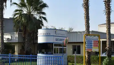 "Scott Bader manufacturing facility entrance with palm trees, showcasing the company's production site for composites and resins" [G]