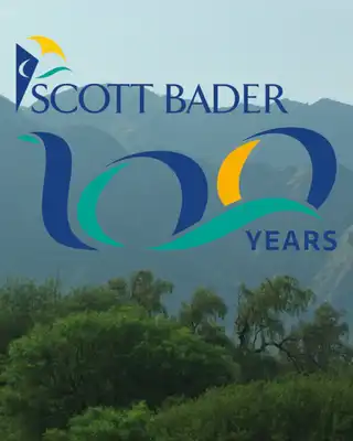 "Scott Bader 100 years anniversary logo displayed against a scenic mountain landscape backdrop" [G]
