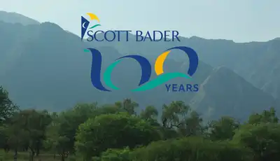 "Scott Bader 100 years anniversary logo displayed against a scenic mountain landscape backdrop" [G]