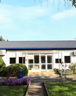 "Scott Bader manufacturing facility with blue-roofed building surrounded by landscaped grounds and shrubs" [G]
