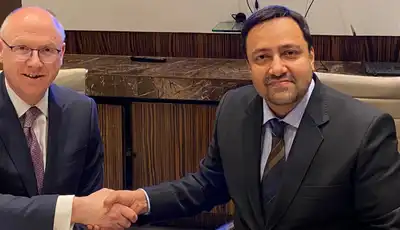 "Two business professionals shaking hands at a meeting with wood-paneled backdrop, representing Scott Bader's partnership in adhesives and composites" [G]