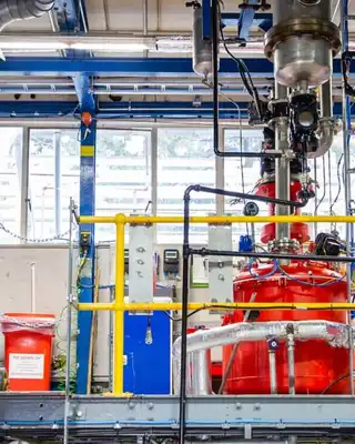 "Industrial manufacturing facility with red processing equipment and complex piping system for Scott Bader resins and composites production" [G]