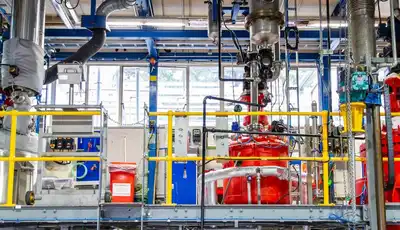 "Industrial manufacturing facility with red processing equipment and complex piping system for Scott Bader resins and composites production" [G]