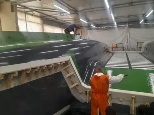 Workers applying Scott Bader gelcoats and resins during large composite boat hull manufacturing. [G]