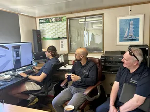Scott Bader team collaborating in office reviewing composite design on screen with sailboat art [G]