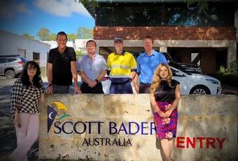 "Group gathered at Scott Bader Australia entrance sign, showcasing the company's composites and adhesives expertise" [G]