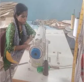 "Textile worker operating a sewing machine in a manufacturing workshop with fabric materials and supplies" [G]