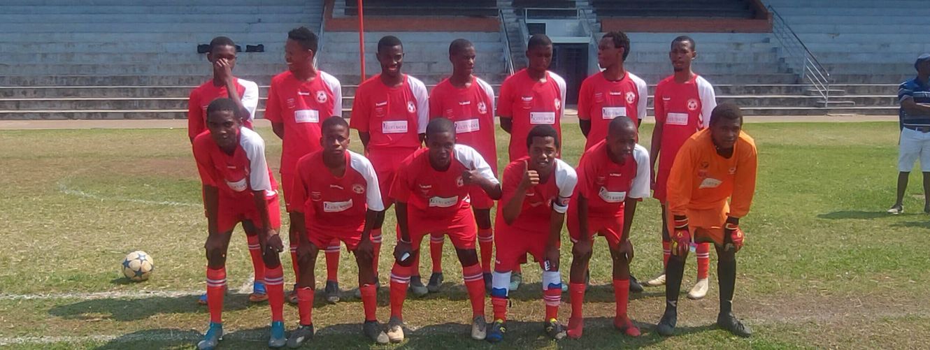 "Soccer team in red uniforms posing on field with stadium seating in background" [G]