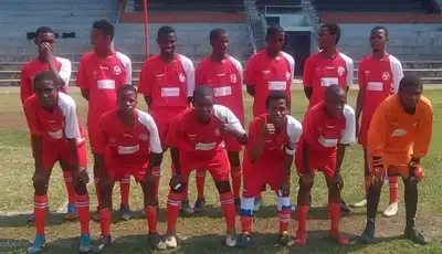 "Soccer team in red uniforms posing on field with stadium seating in background" [G]