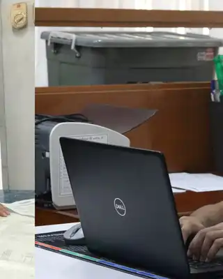 "Two professionals working in a Scott Bader office environment - one examining documents while another uses a laptop" [G]