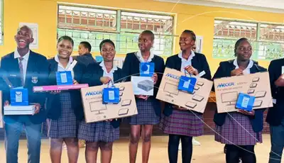 Students in school uniforms holding donated boxes, community outreach supported by Scott Bader. [G]