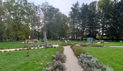 "Landscaped park area with stone-lined pathway, green lawns, and decorative plants surrounding Scott Bader facility" [G]