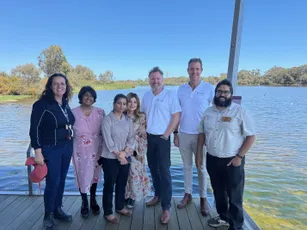 "Group gathered on wooden dock overlooking water on sunny day with clear blue sky" [G]