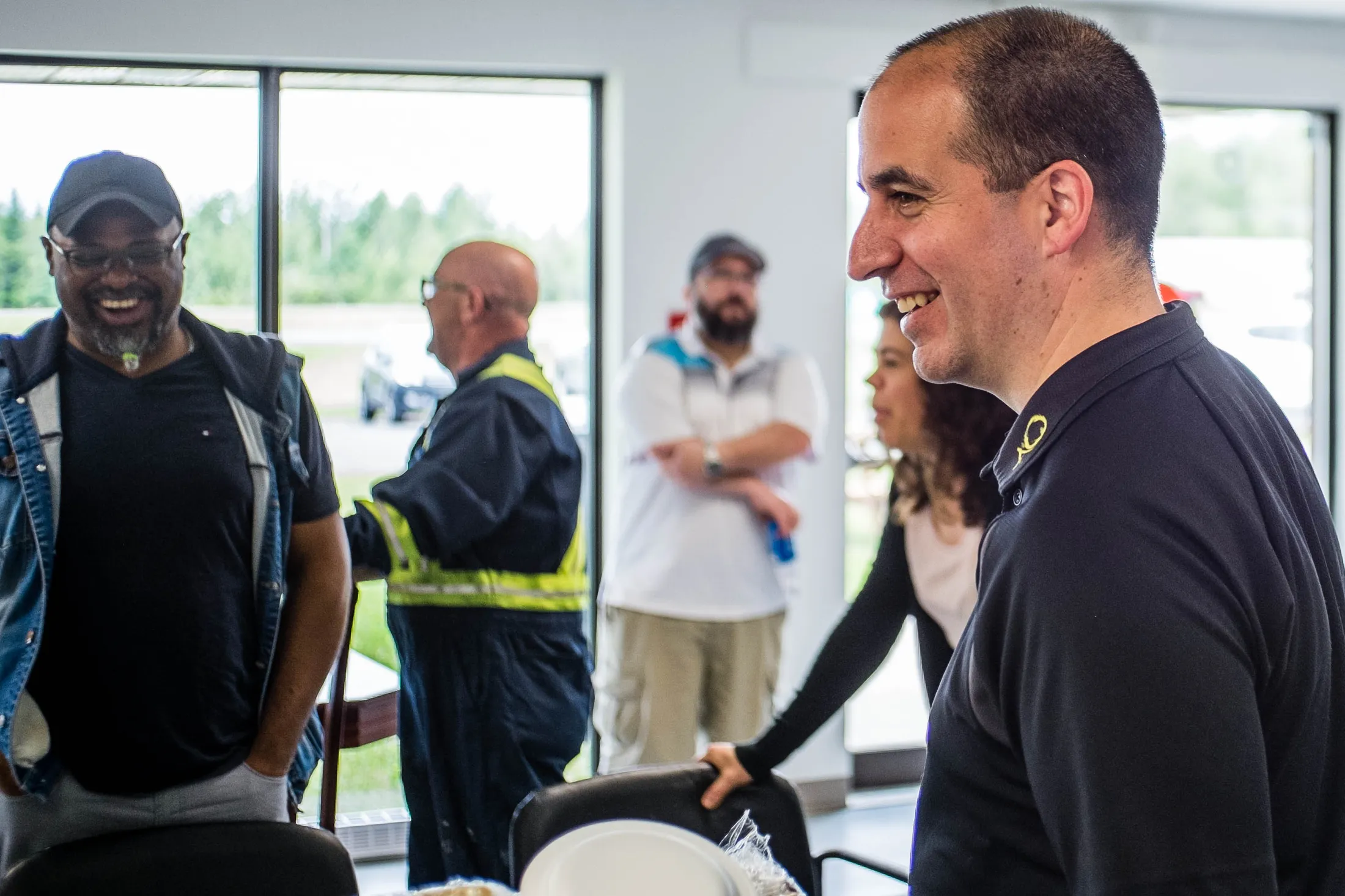 "Professional networking event at Scott Bader facility with attendees engaged in conversation in bright modern space" [G]