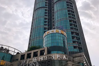 Modern glass skyscraper with King Glory Plaza and Hitech Plaza signage against cloudy sky. [G]