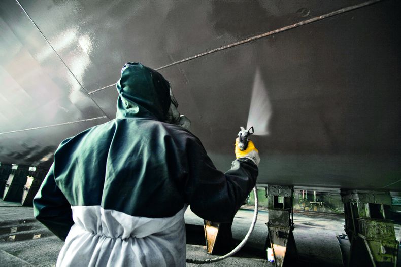 "Worker applying Scott Bader gelcoats to boat hull in manufacturing facility, showcasing marine composites application" [G]