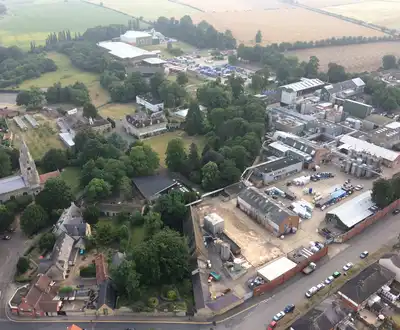 "Aerial view of Scott Bader manufacturing facility surrounded by countryside, showcasing the company's composites and resins production site." [G]