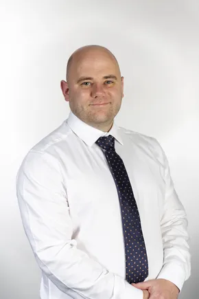 Professional portrait of a Scott Bader team member in white shirt and patterned tie against neutral background [G]