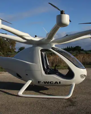 "White electric aircraft with multiple rotors on a rural airstrip, showcasing lightweight composites for advanced transportation" [G]