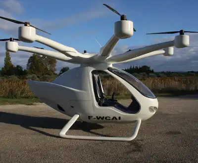 "White electric aircraft with multiple rotors on a rural airstrip, showcasing lightweight composites for advanced transportation" [G]