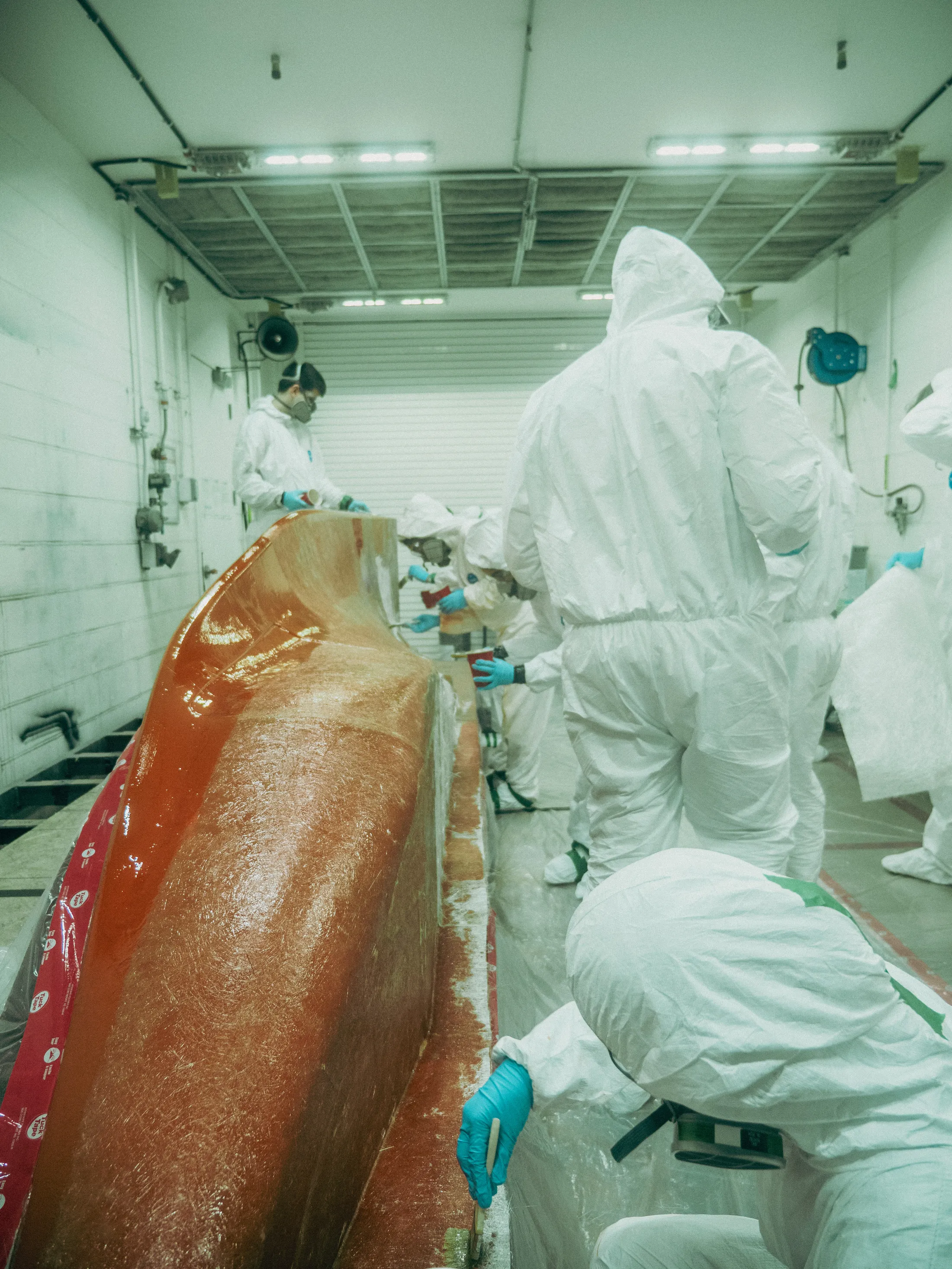 Workers applying Scott Bader gelcoats and composites during boat hull manufacturing process. [G]