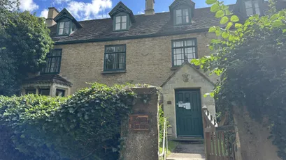 Historic stone building exterior with green door, ivy, and dormer windows [G]
