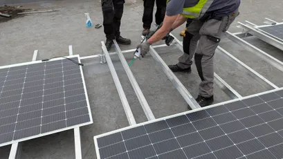 "Workers installing solar panels on metal framework using Scott Bader structural adhesives for secure mounting" [G]