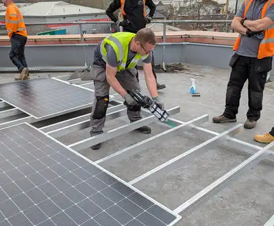 "Construction workers installing solar panels on a flat roof, using Scott Bader structural adhesives for secure mounting" [G]