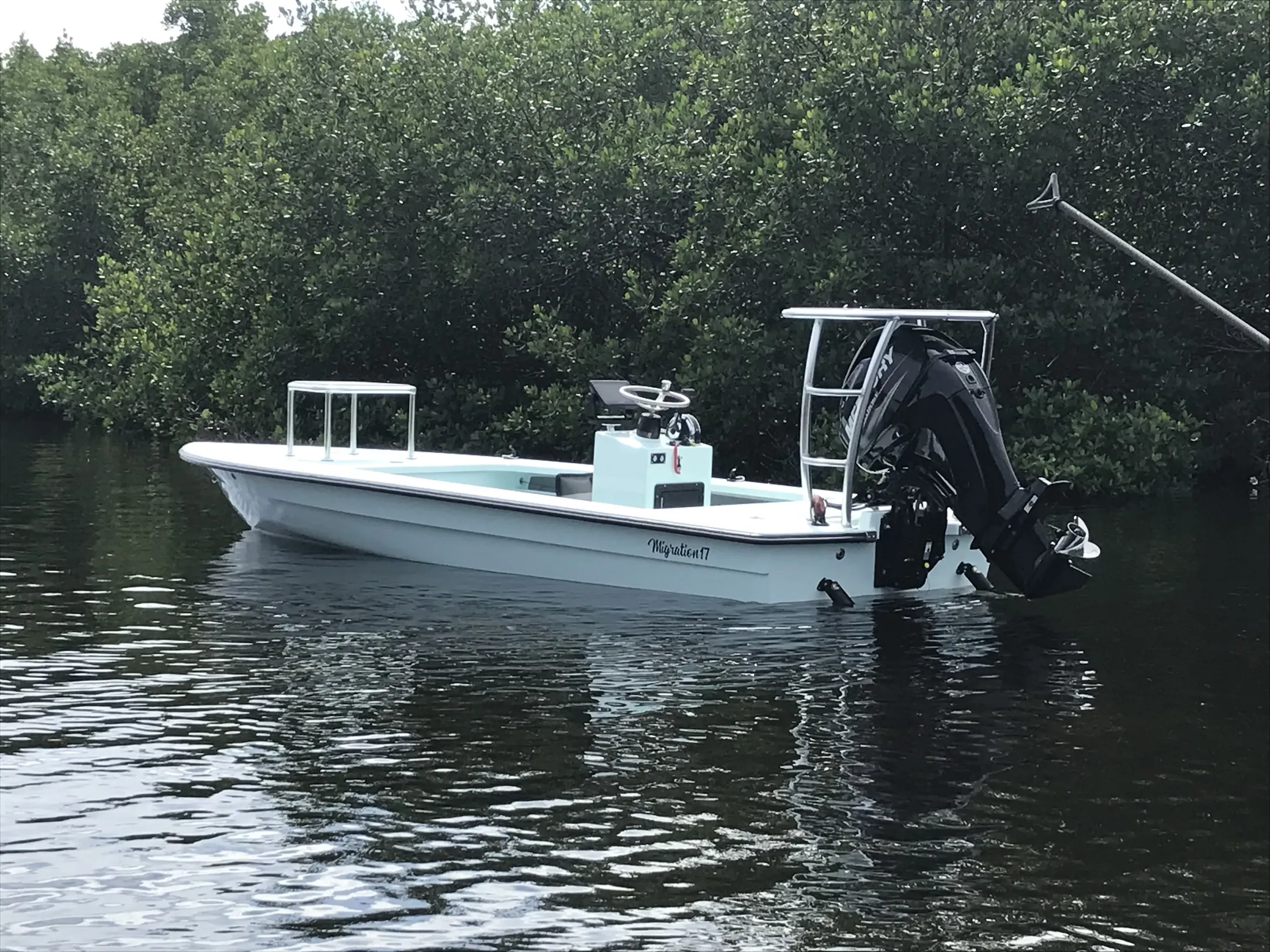 "White fishing boat with outboard motor navigating through mangroves, showcasing Scott Bader gelcoats and composites for marine applications" [G]