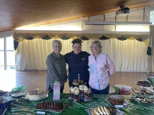 "Event at Scott Bader featuring a display of desserts and baked goods with decorative table setting in a wood-paneled venue" [G]