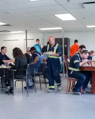 "Scott Bader employees in safety workwear enjoying lunch in company cafeteria, showcasing workplace culture in composites manufacturing" [G]