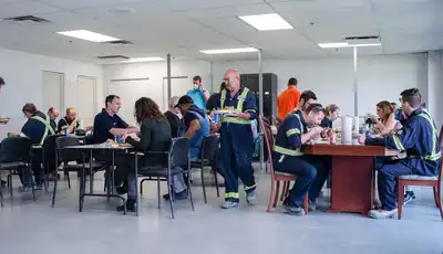"Scott Bader employees in safety workwear enjoying lunch in company cafeteria, showcasing workplace culture in composites manufacturing" [G]