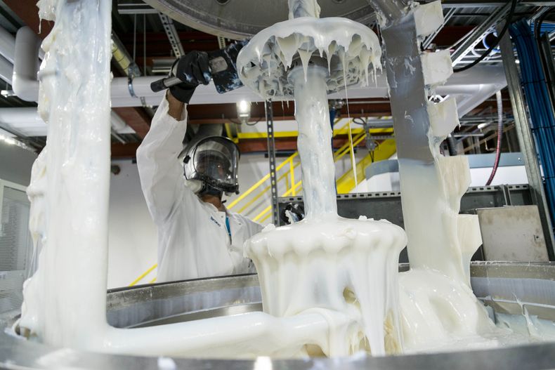 "Technician in protective gear working with Scott Bader gelcoats during manufacturing process, showcasing resin application" [G]