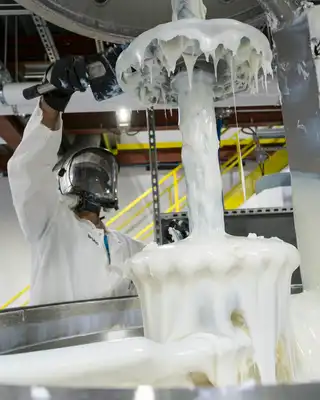 "Technician in protective gear working with Scott Bader gelcoats during manufacturing process, showcasing resin application" [G]