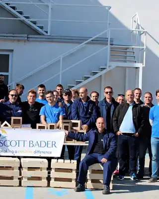 "Team of manufacturing professionals gathered outside Scott Bader facility, showcasing the company's composites and resins expertise" [G]