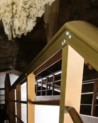 "Interior view of a cave with stalactites and wooden walkway structure, illuminated by soft lighting" [G]